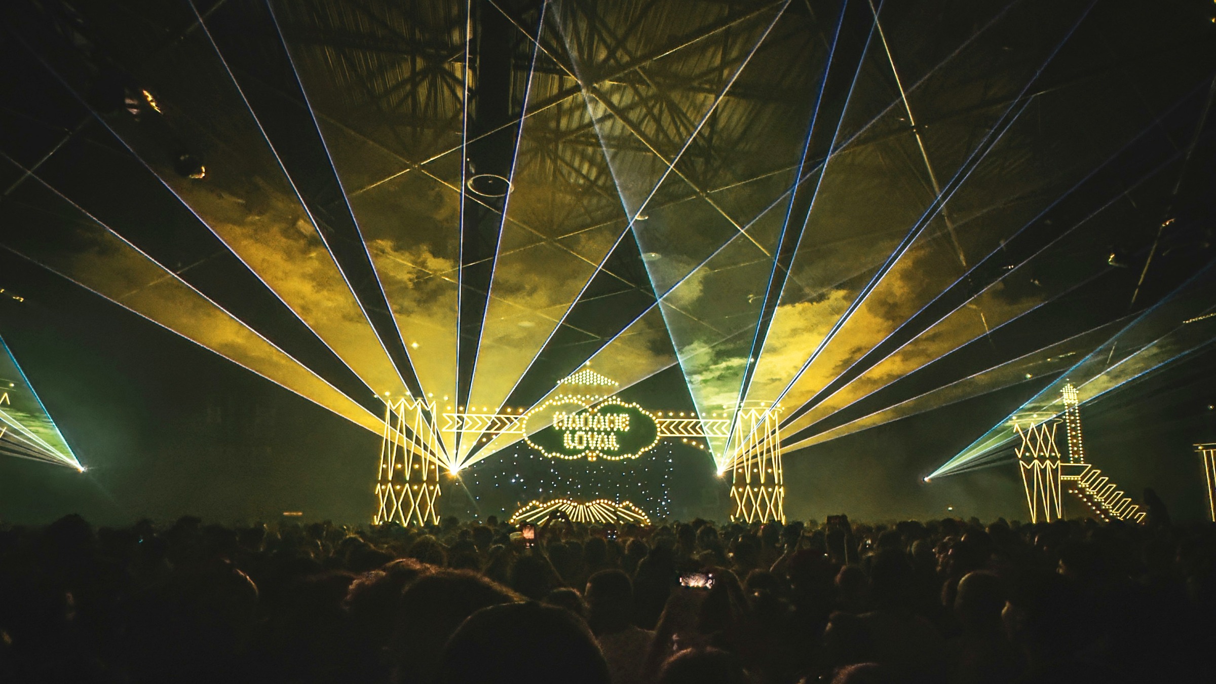 A wide nighttime concert crowd facing a brightly lit stage